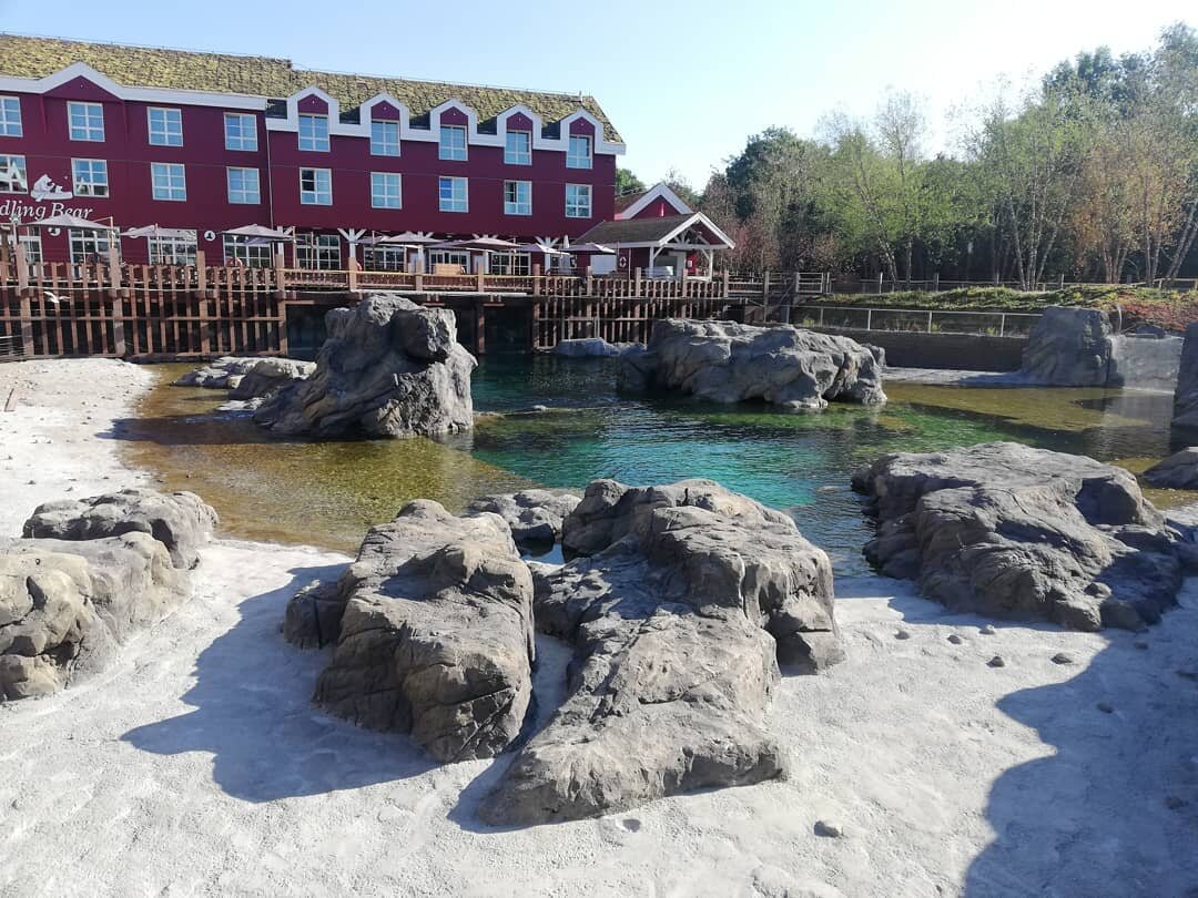 Artificial rock lake beside a themed building at Pairi Daiza